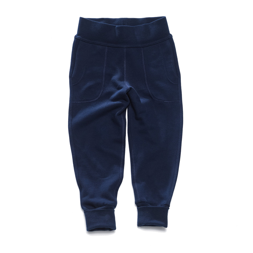 A pair of navy children's pants with flatlocked seams, top stitched waistband, and  grow with me cuffs rolled up slightly.