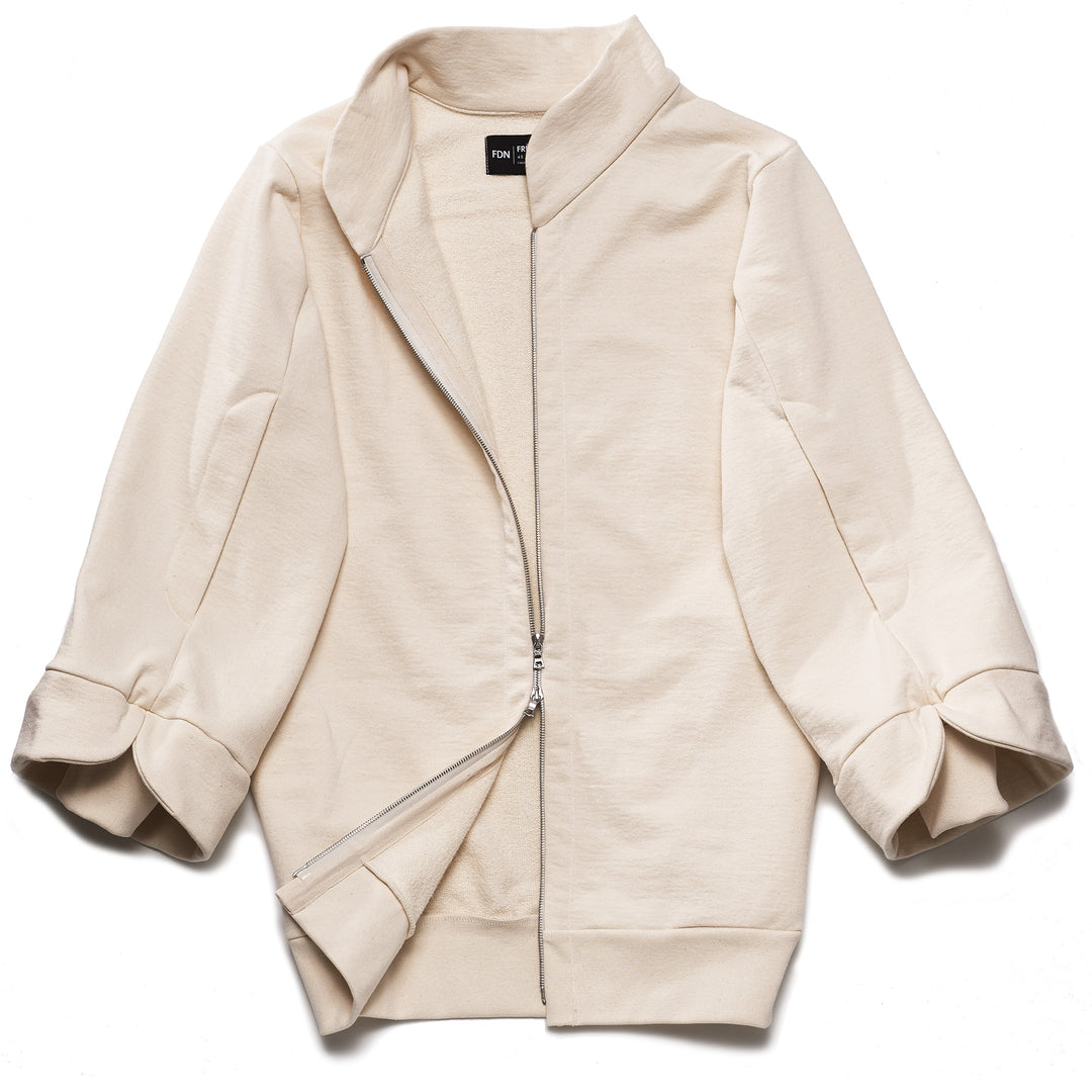 A beige, oversized tulip-shaped sleeve coat with a rib cuff and a matching petal collar, featuring a 2-way riri metal zipper and side pockets.