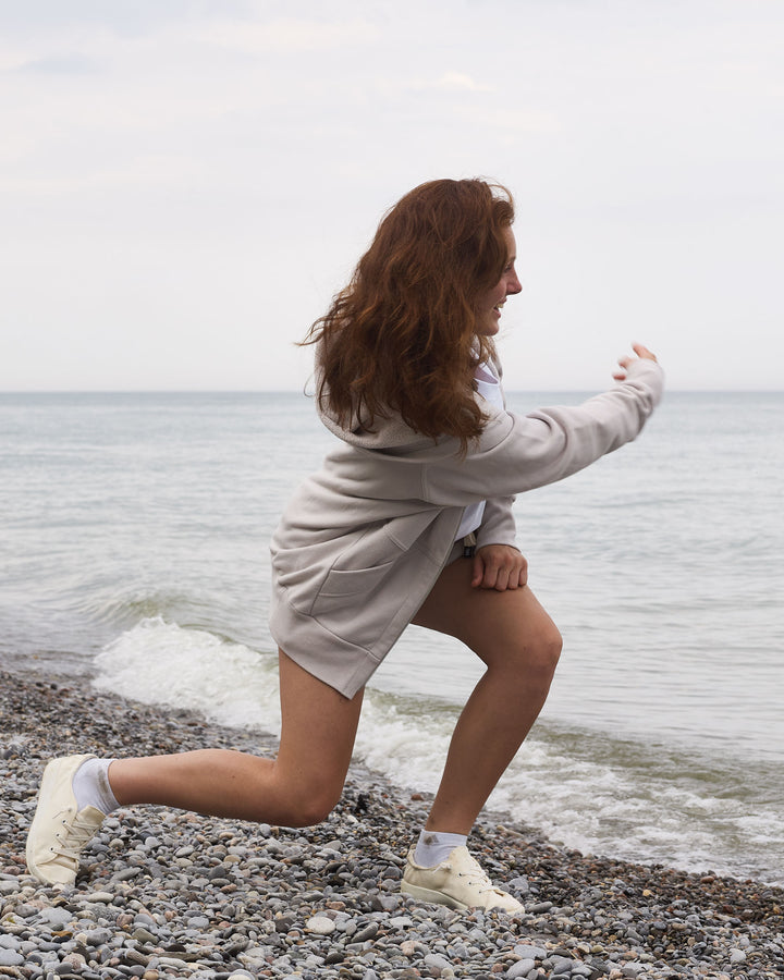 Summer Zip Up Hoodie - Limestone (Light Grey) - Beach Lifestyle Shot Skipping Rocks - 2-Way RiRi Zipper - 100% Cotton French Terry - Made in Canada - FRÈRE DU NORD
